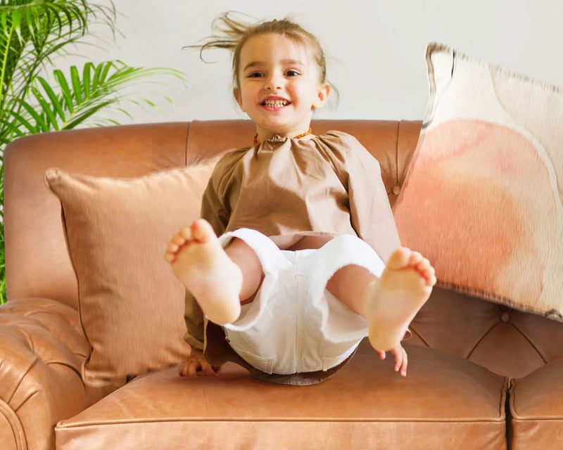 Girl jumping on leather sofa