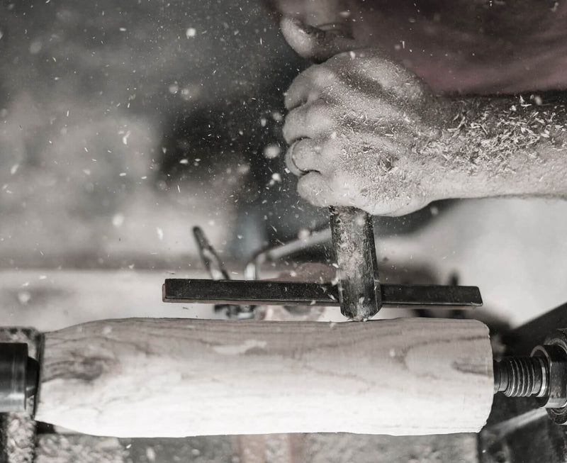 Hand turning a solid wood leg for a sofa on a lathe 